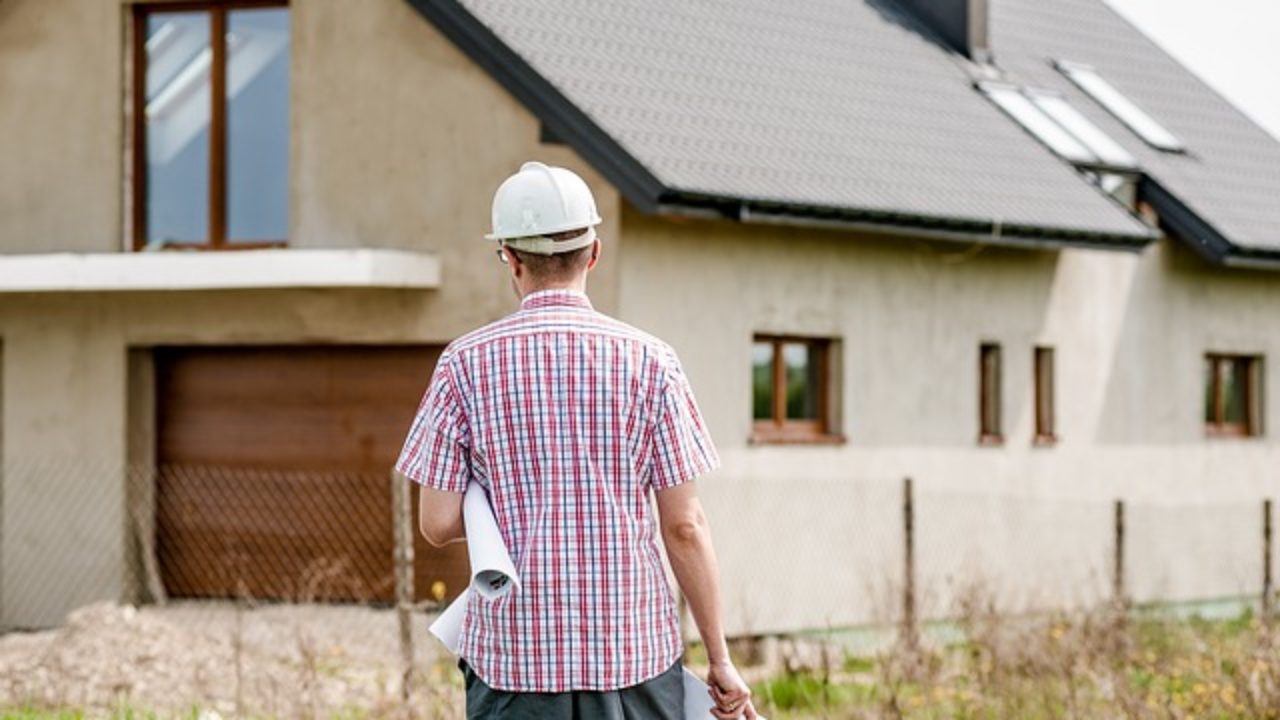 a man in a hardhat walks towards a house