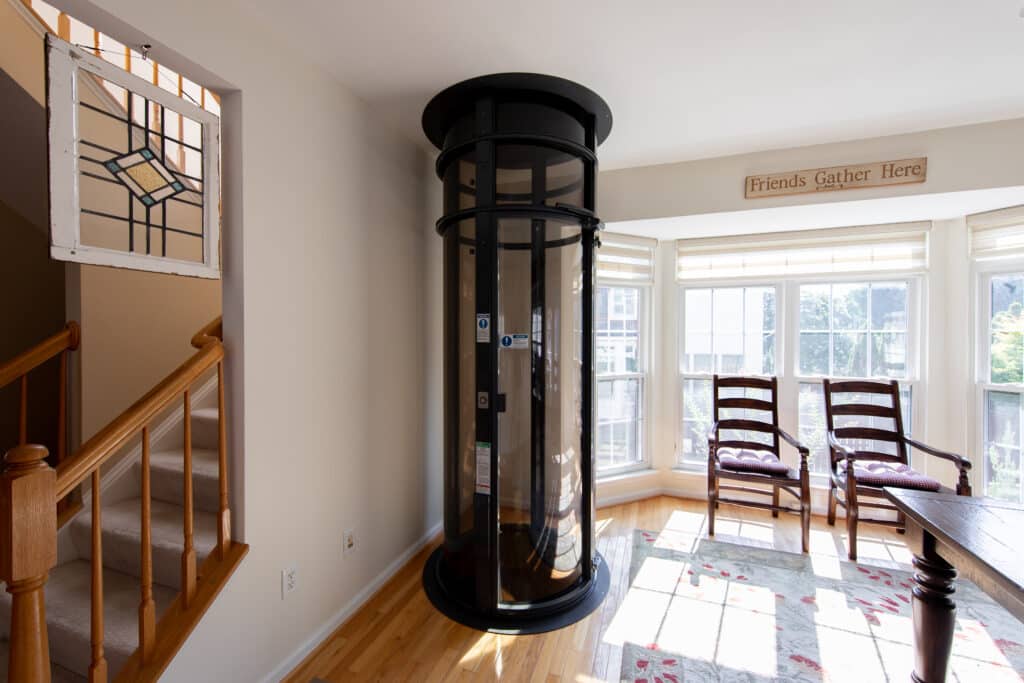 Black framed vacuum elevator tube installed in a home's bright dining area.