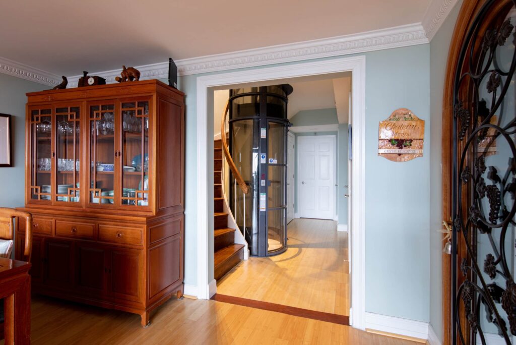 A home elevator can be seen next to a staircase through a hallway entrance.