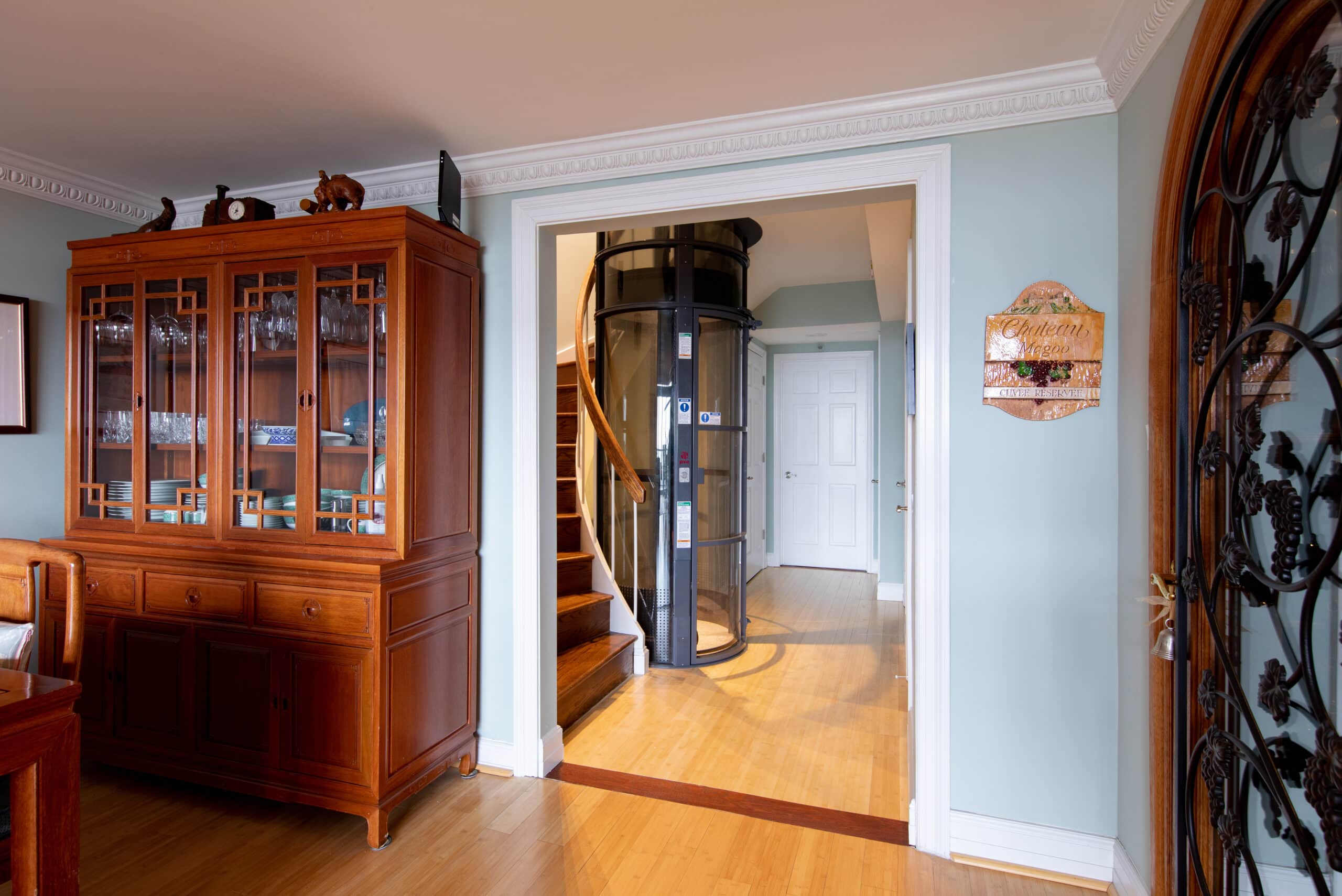 A home elevator is can be seen next to a staircase through a hallway entrance.