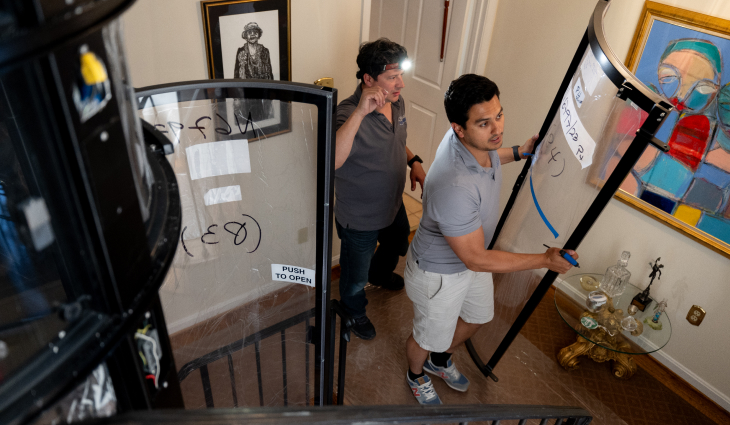 Two technicians installing home elevator door